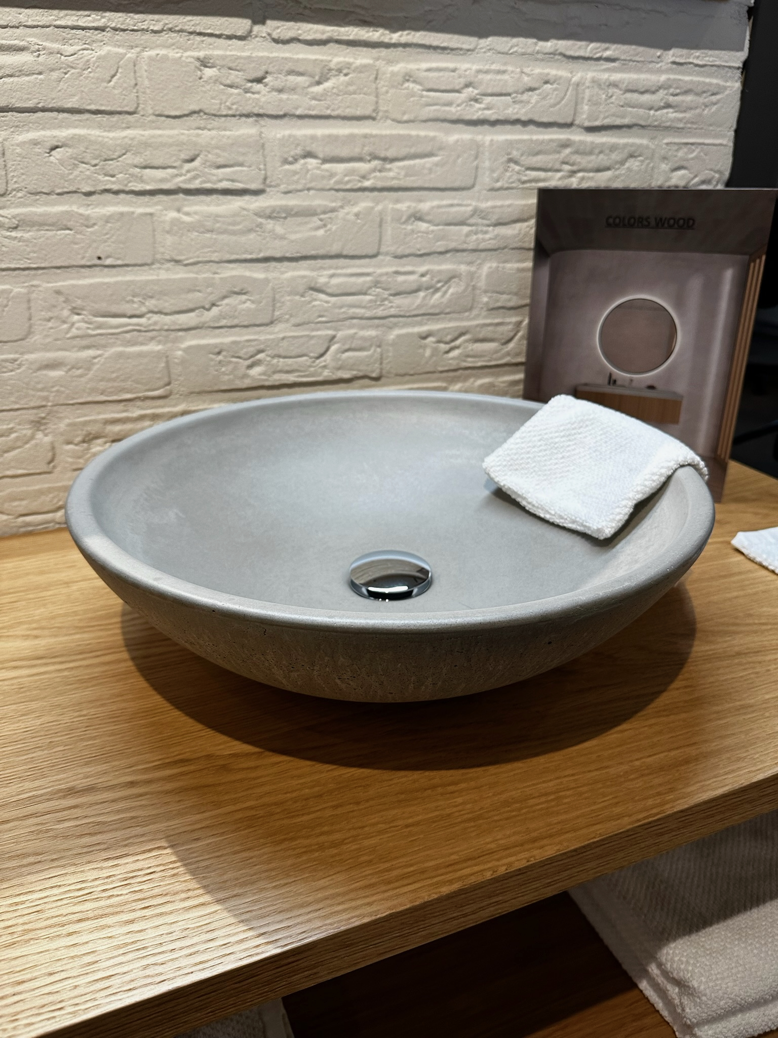 Grijze wastafel Een grijze wastafel op een houten badmeubel met een washandje